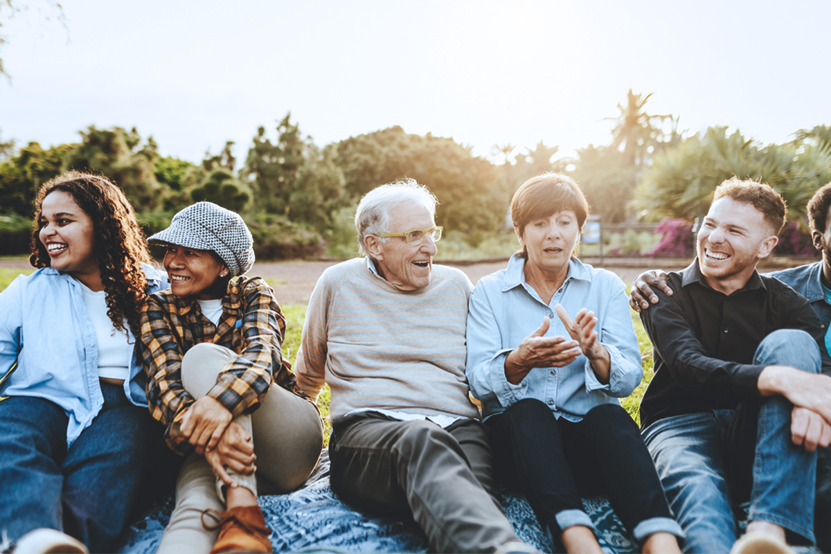 A diverse group of people smiling and relaxing in a park